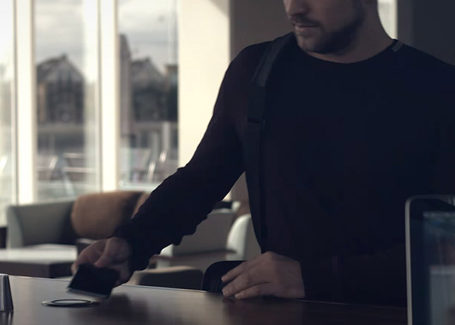 Image of guy from website video placing phone on charger in hotel